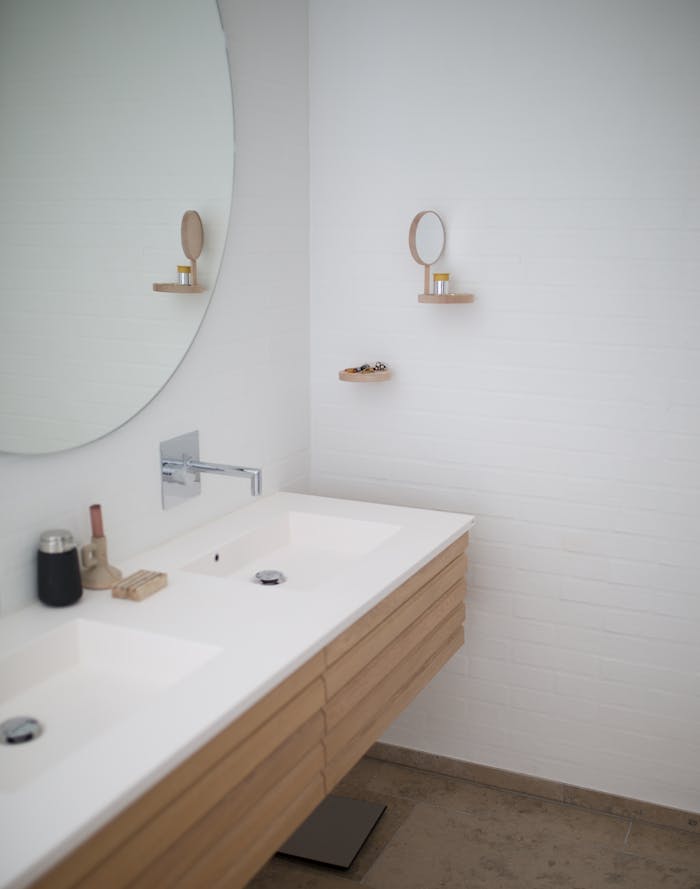 Sleek minimalist bathroom design with double sink and round mirror, showcasing modern interior design.